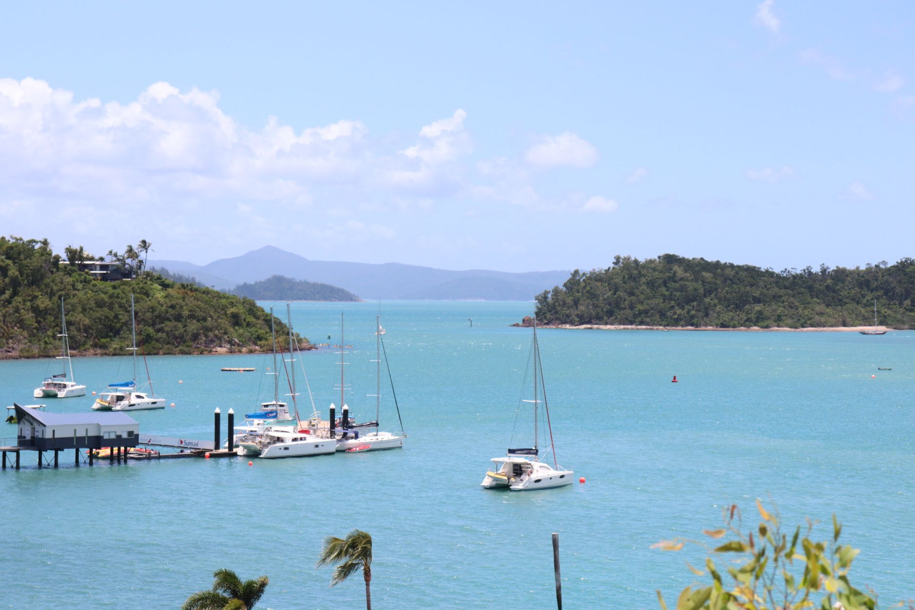 Sailboats anchored in tropical turquoise waters, surrounded by green islands