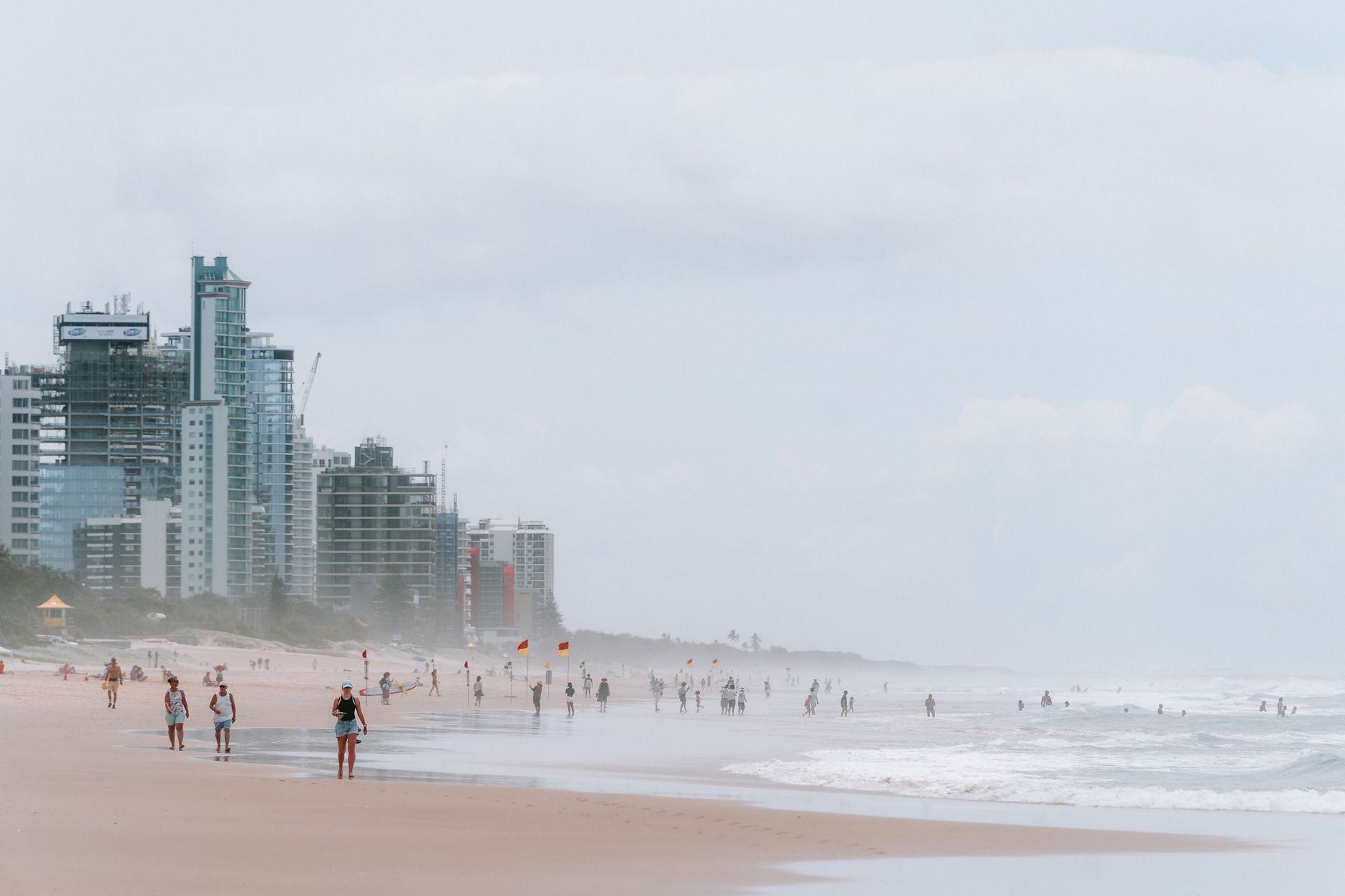 Surfers Paradise beach with people walking on the sand and tall buildings in the background