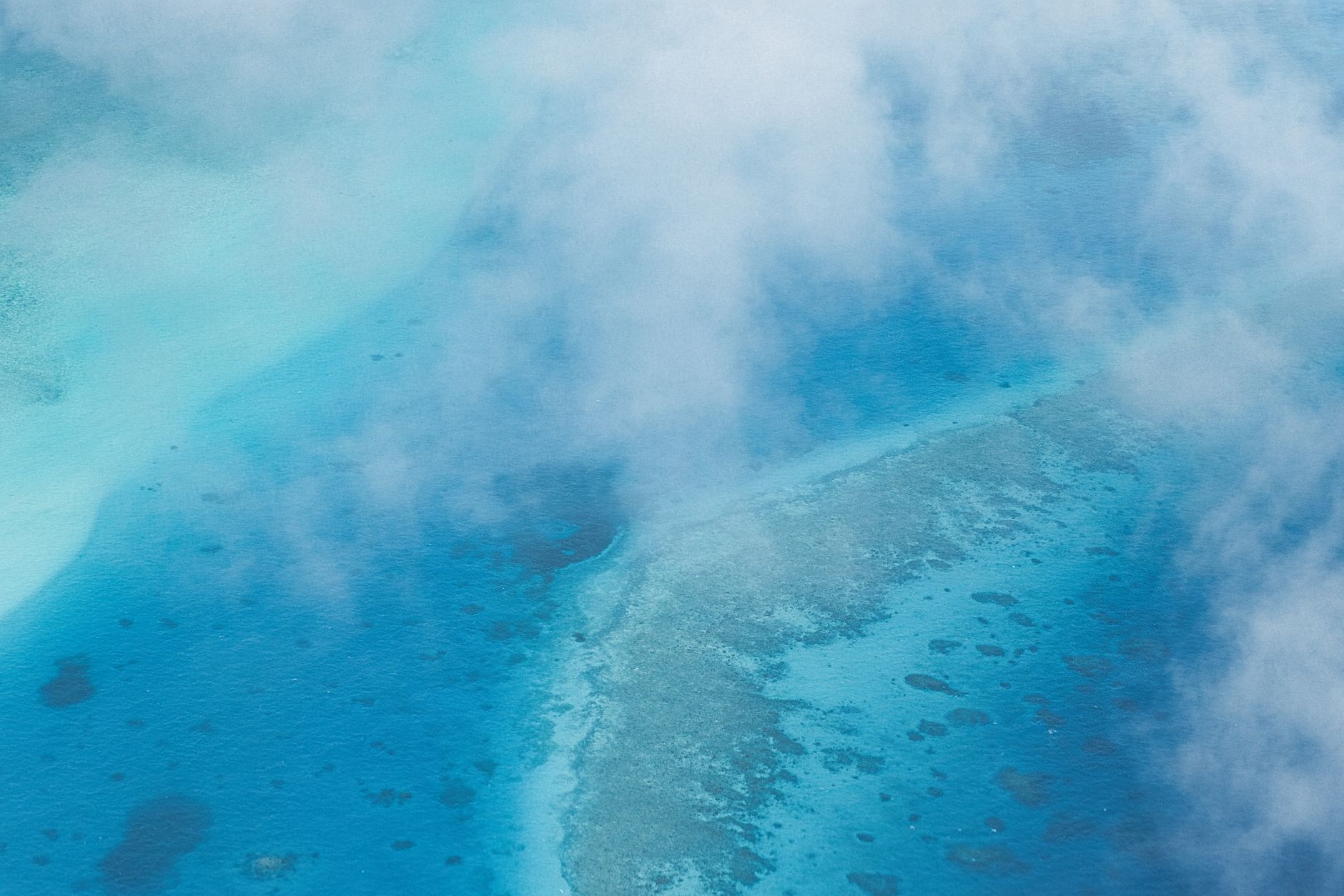 Aerial view of the Great Barrier Reef, with coral formations visible through the turquoise water