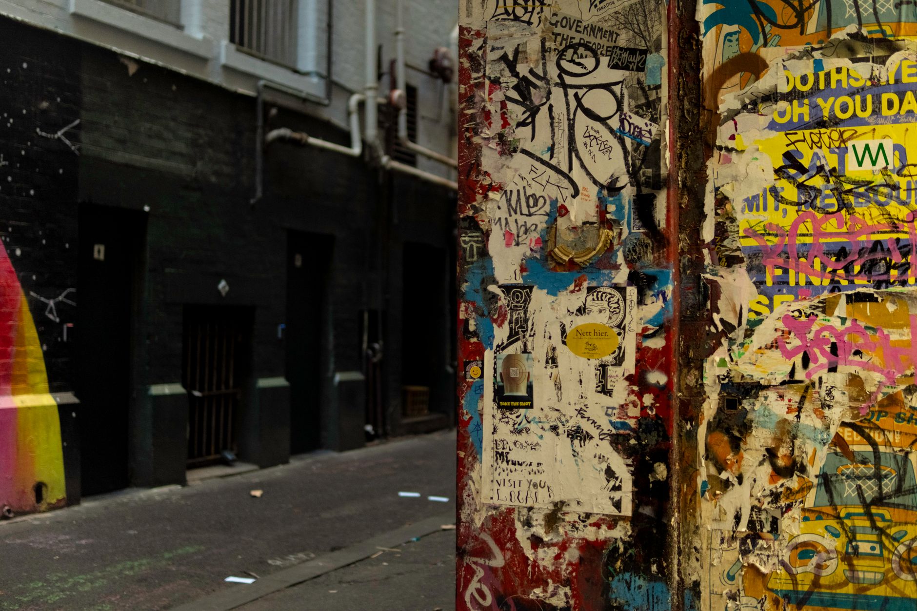 Callejón de Melbourne con paredes cubiertas de grafiti y carteles coloridos