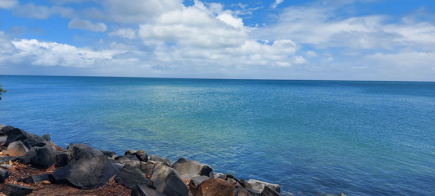 Costa rochosa de Hervey Bay, com águas calmas e azuis sob céu parcialmente nublado