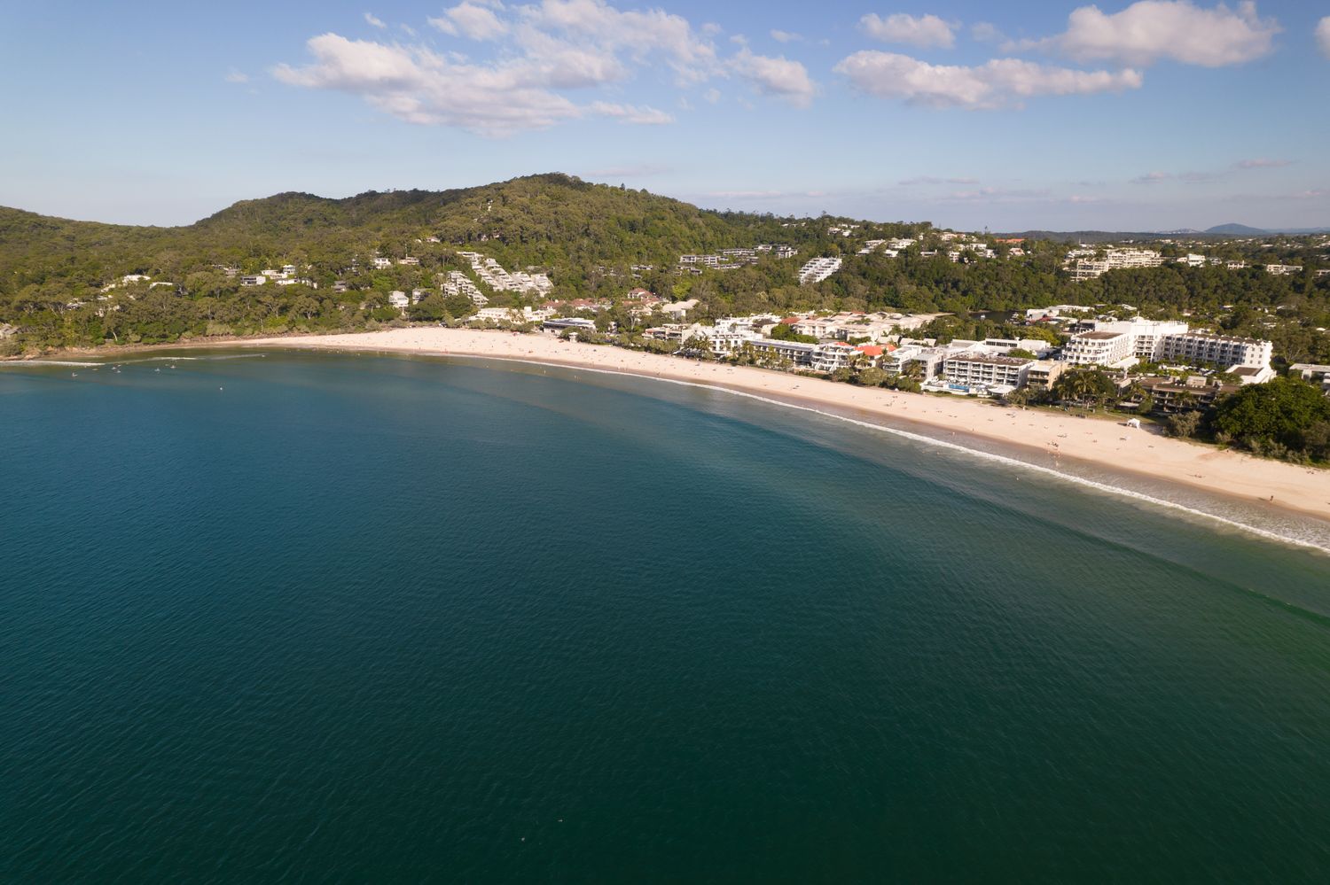 Vista aérea de Noosa Heads, com a orla urbanizada ao lado da praia e mata ao redor