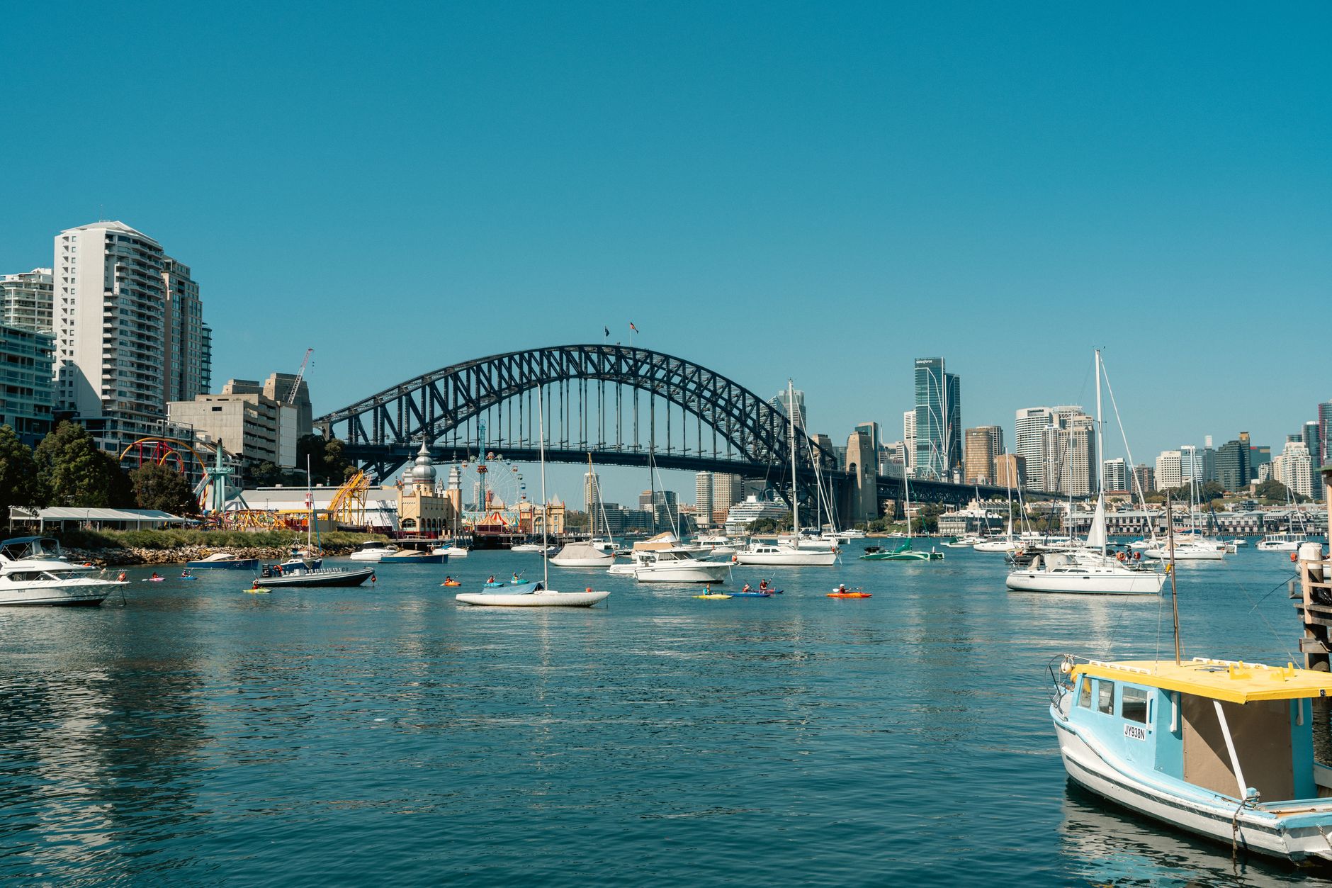 Sydney Harbour Bridge seen from the harbour, with boats moored, Luna Park and the city skyline in the background