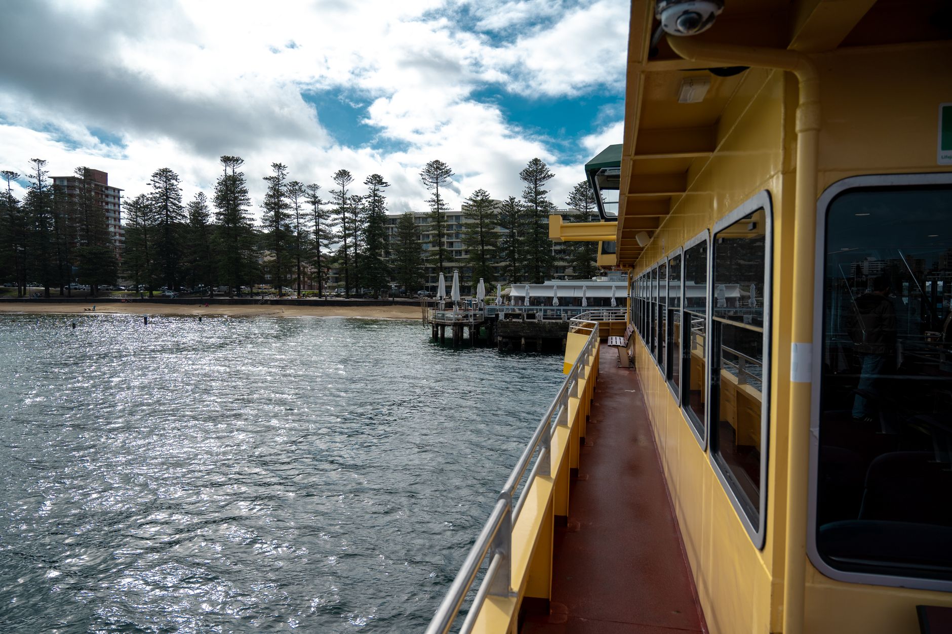 View of the ferry approaching Manly Beach, with buildings and trees along the shore