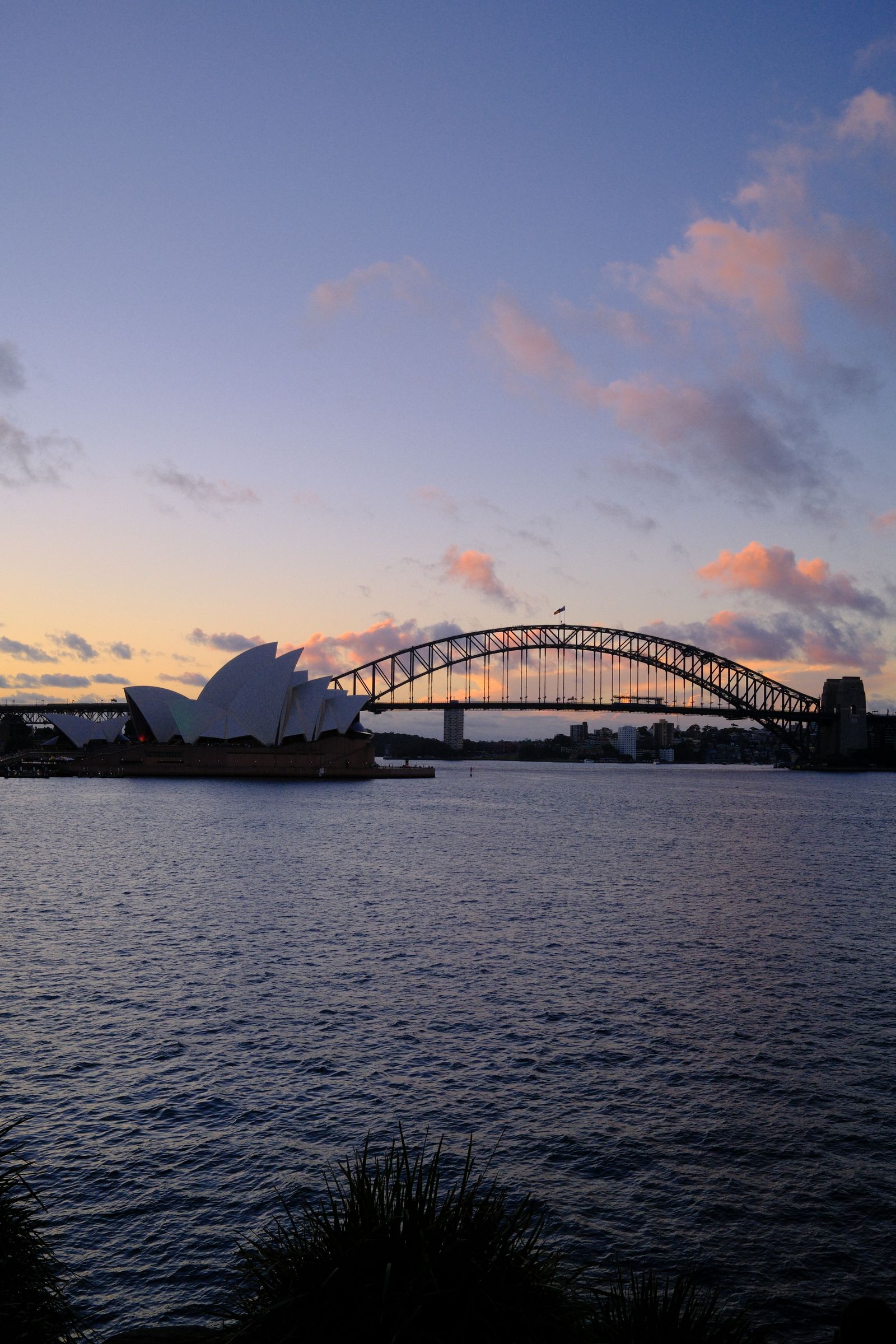 Sydney Opera House and Harbour Bridge seen at dusk, in the same photo, from the opposite side of the harbour
