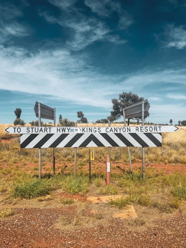 Cartel de ruta en el Territorio del Norte indicando la Stuart Highway y Kings Canyon Resort, rodeado de vegetación del Outback