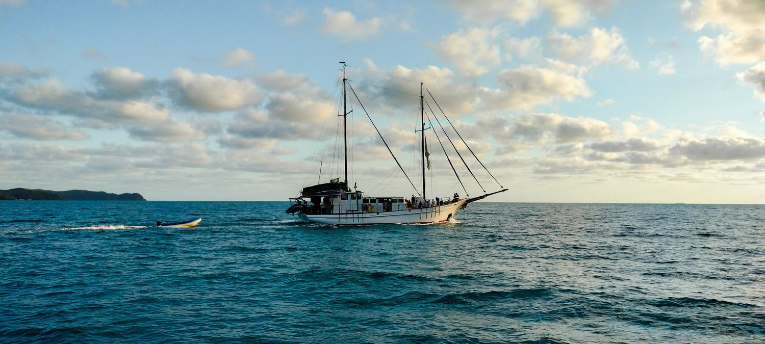 Day cruise sailboat navigating the turquoise waters of the Whitsundays, with islands in the background
